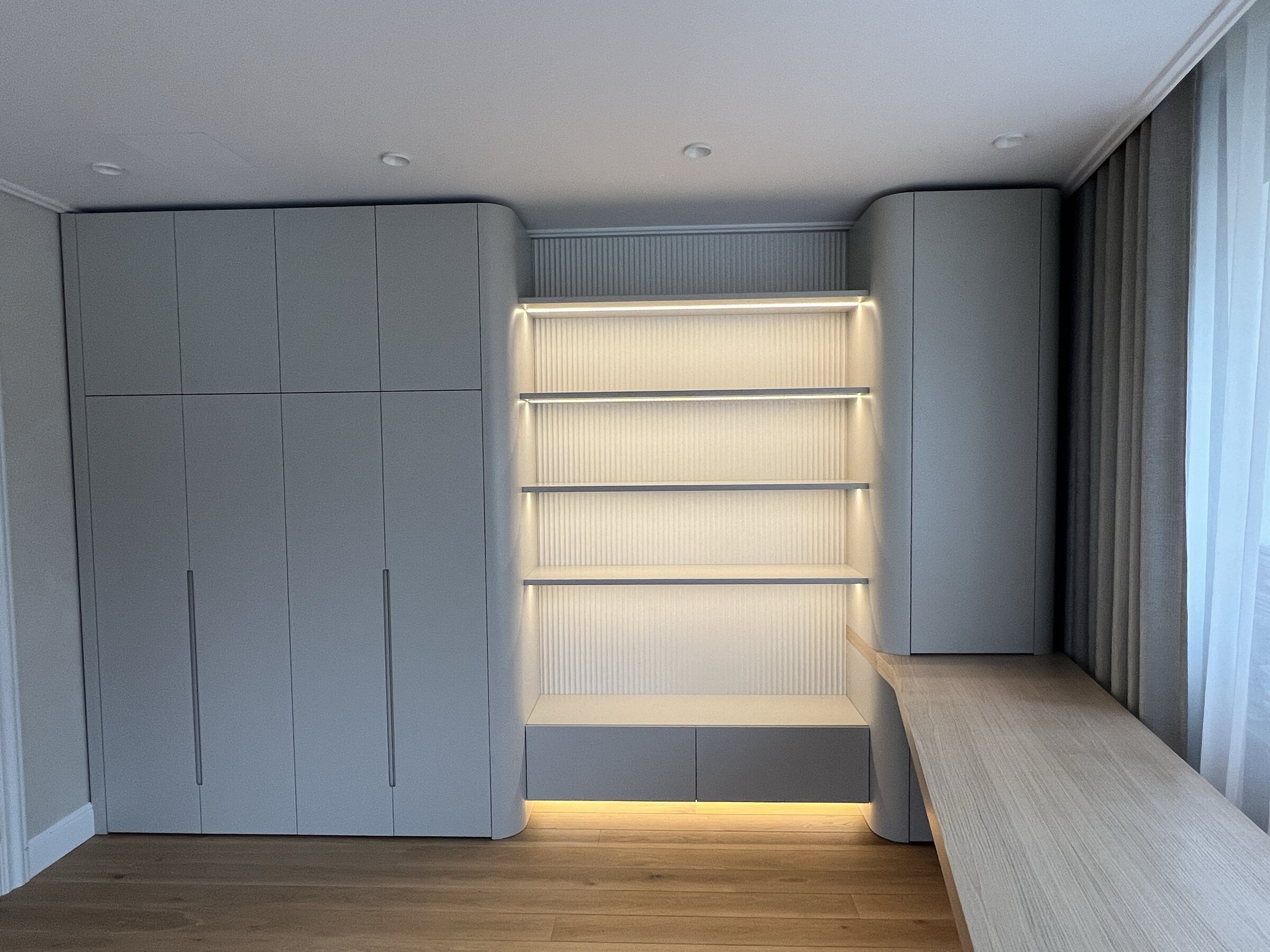Curved fitted storage with integrated illuminated shelving
