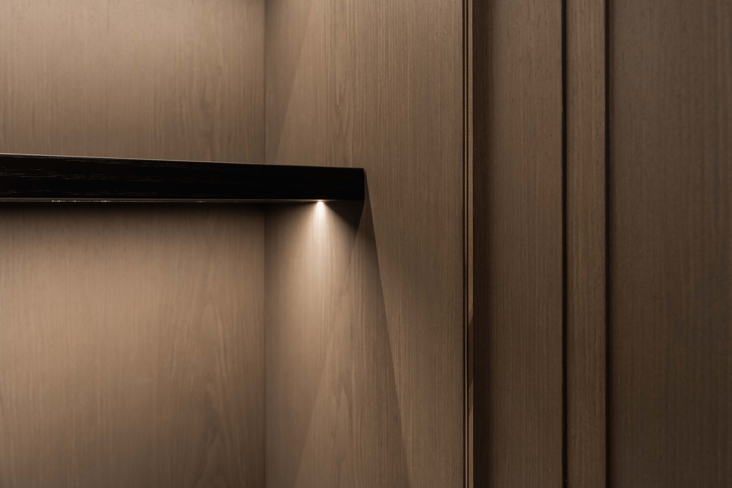 Close-up of veneered panelling, aligned joints and integrated lighting