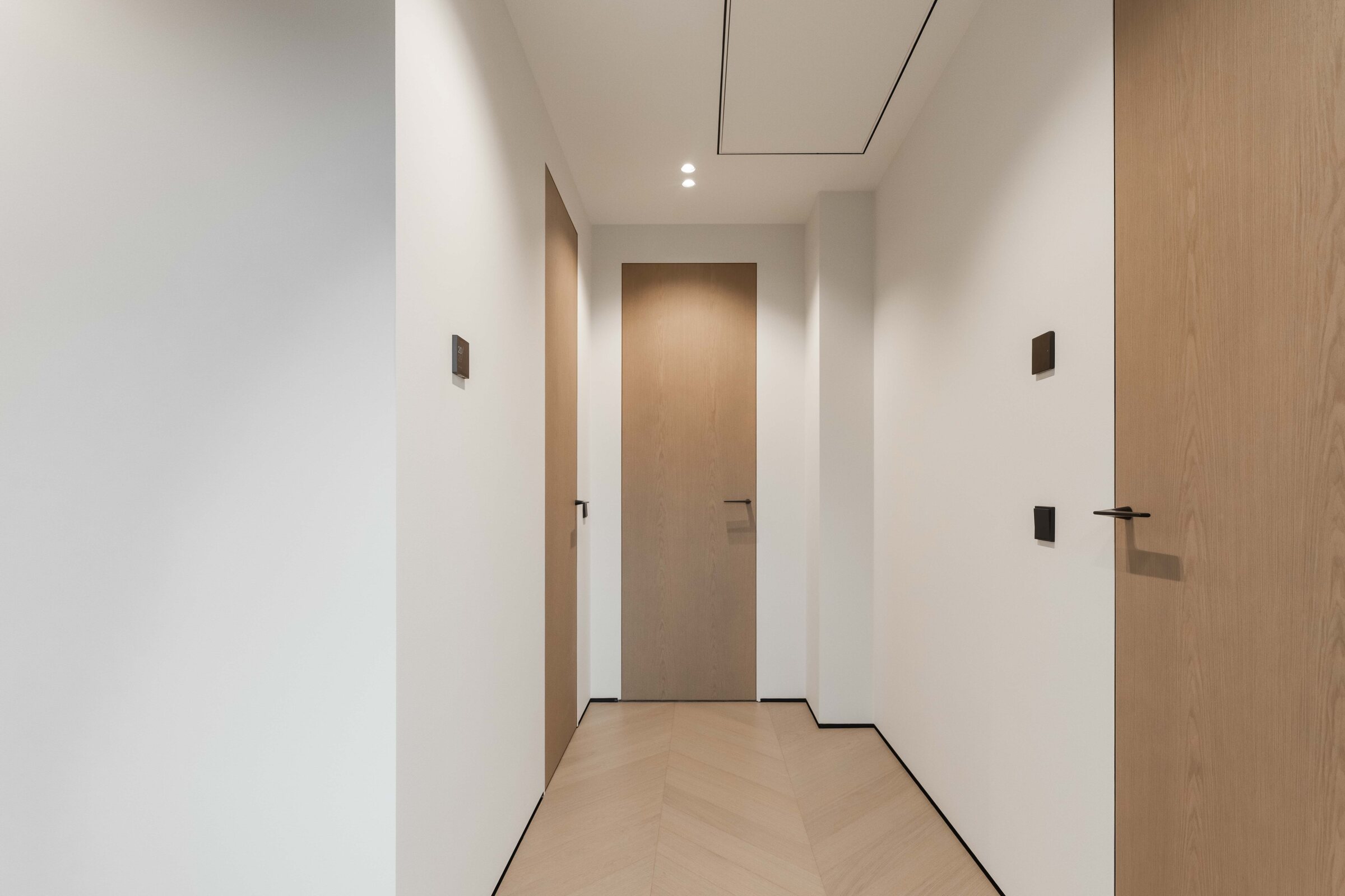 Flush oak doors integrated into a minimal hallway